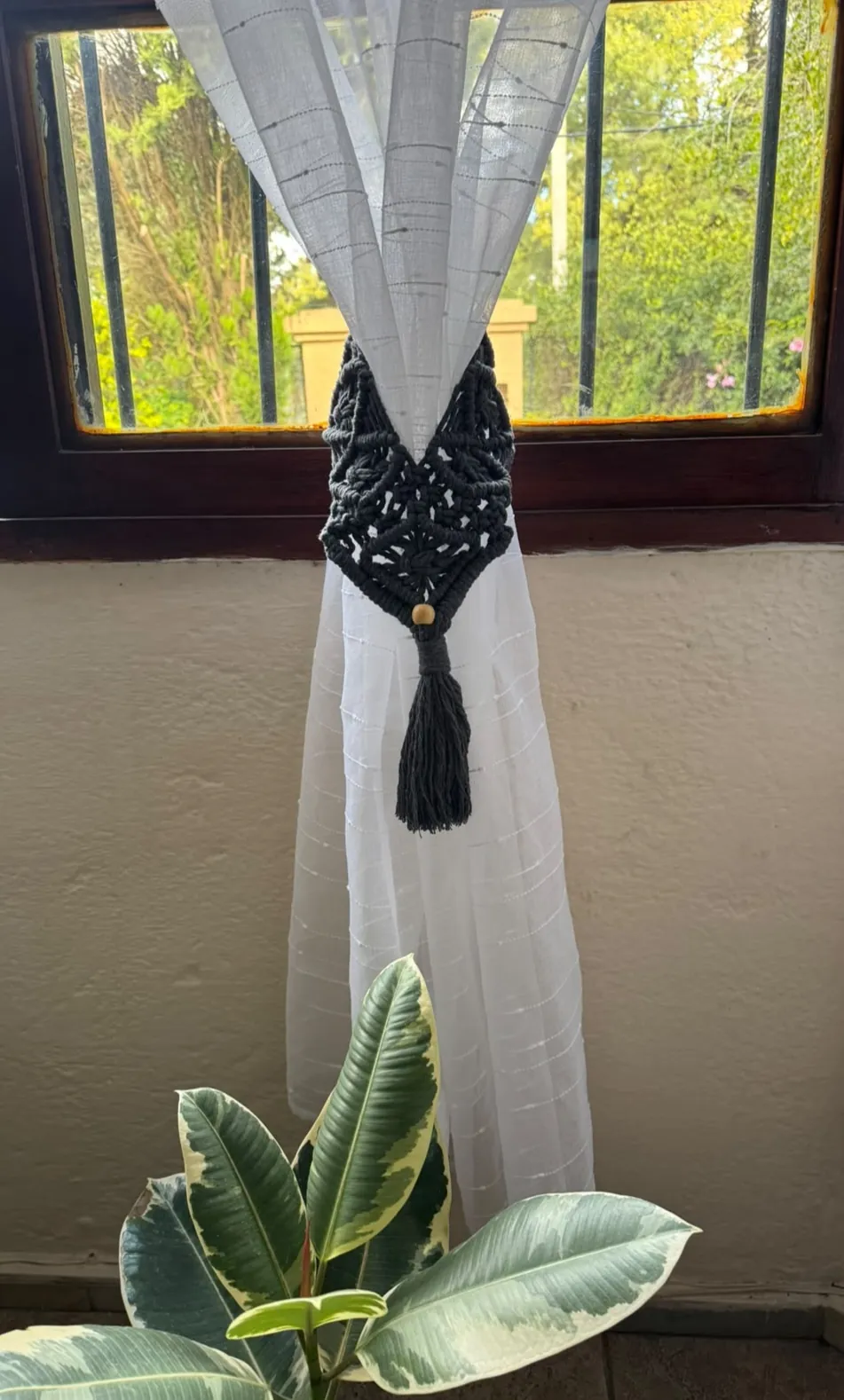 Amarra cortinas de macramé negro con cuenta de madera sobre cortina blanca
