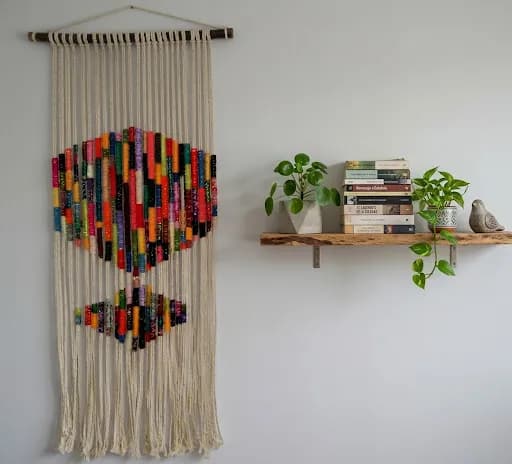 Tapiz de macramé crudo con rombos de colores colgado en la pared